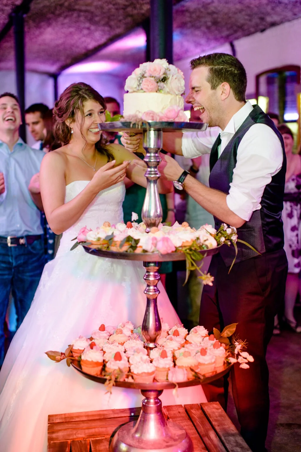 Karin & Tobi | Hochzeitsfotografen aus Köln 6 Braut und Bräutigam schneiden gemeinsam Hochzeitstorte bei Le PomPom Köln mit Cupcakes an
