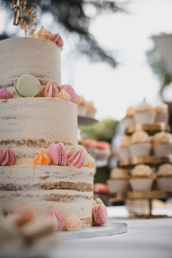 Dreistöckige semi-naked Hochzeitstorte mit bunten Macarons und Baisers im Freien